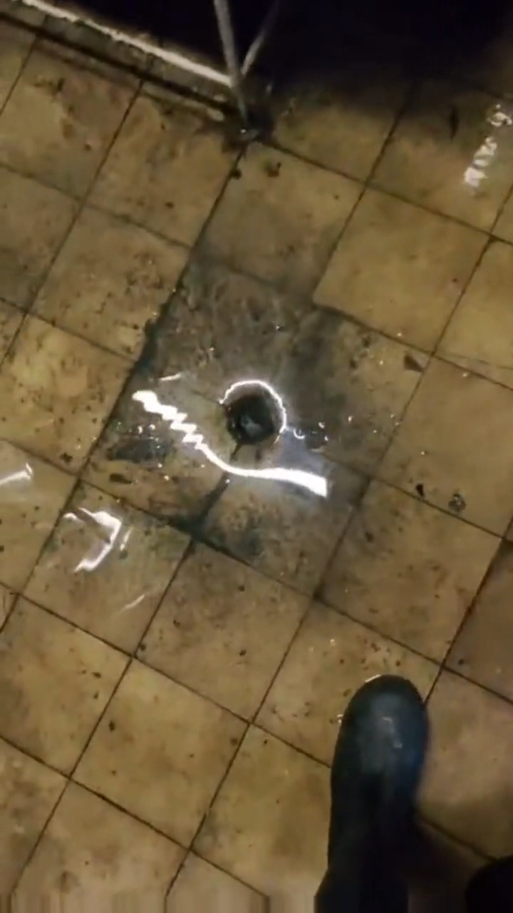 Eau qui remonte par un drain de plancher dans une cuisine de restaurant en raison d’un problème d’écoulement dans la conduite.