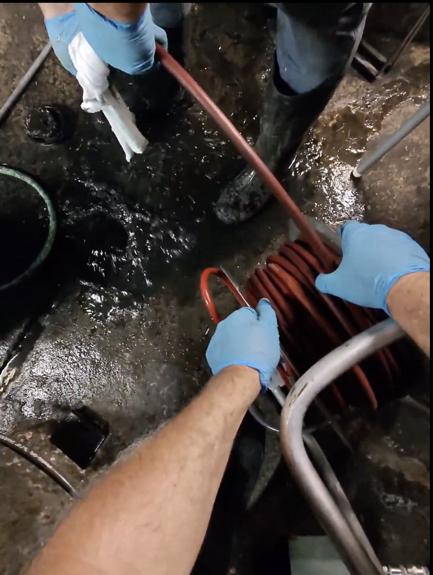 Technicien Flow Pro Drain effectuant un nettoyage par hydrojet d’un drain de plancher dans une cuisine de restaurant afin d’éliminer les accumulations de graisse.