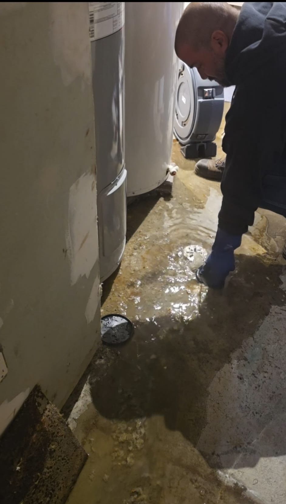 Technicien effectuant le débouchage d’un drain de plancher de sous-sol avec présence d’eau causée par un blocage de la conduite principale.