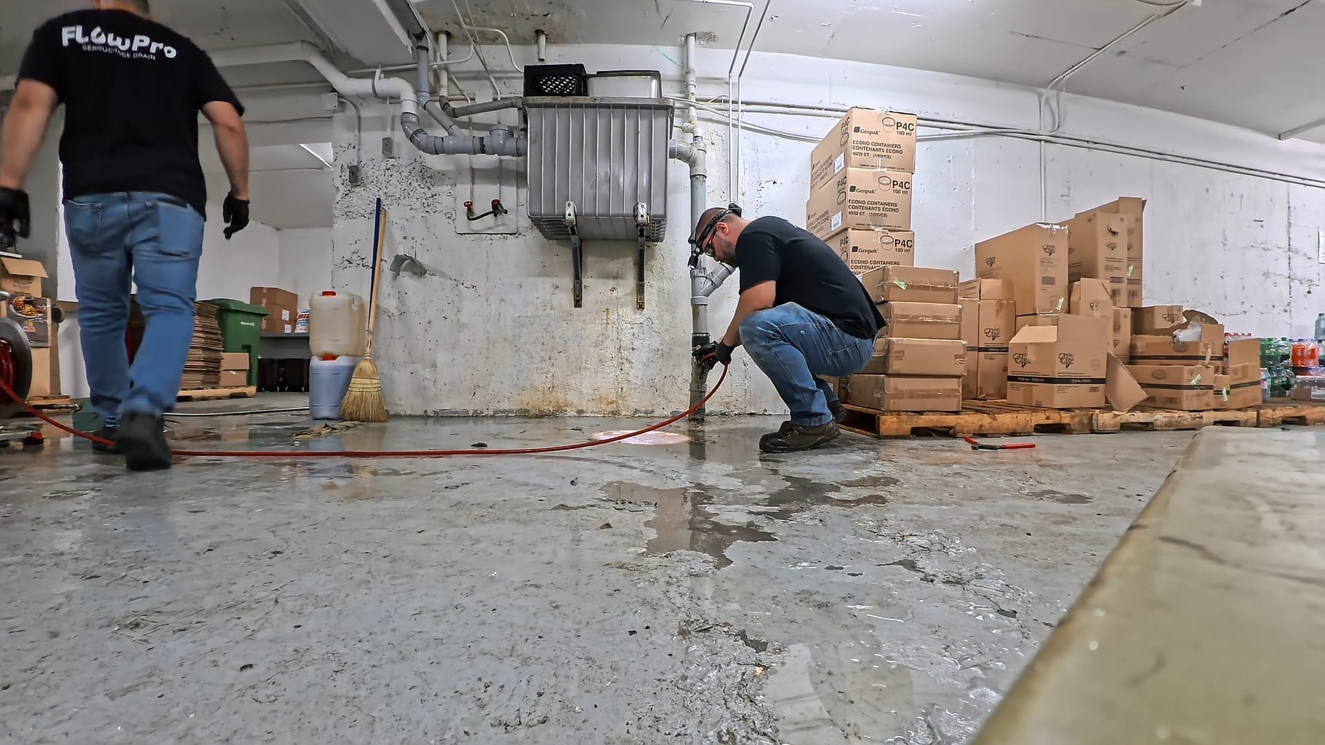Techniciens Flow Pro Drain effectuant le débouchage d’un drain de plancher dans une cuisine commerciale à l’aide d’un équipement professionnel à Montréal.