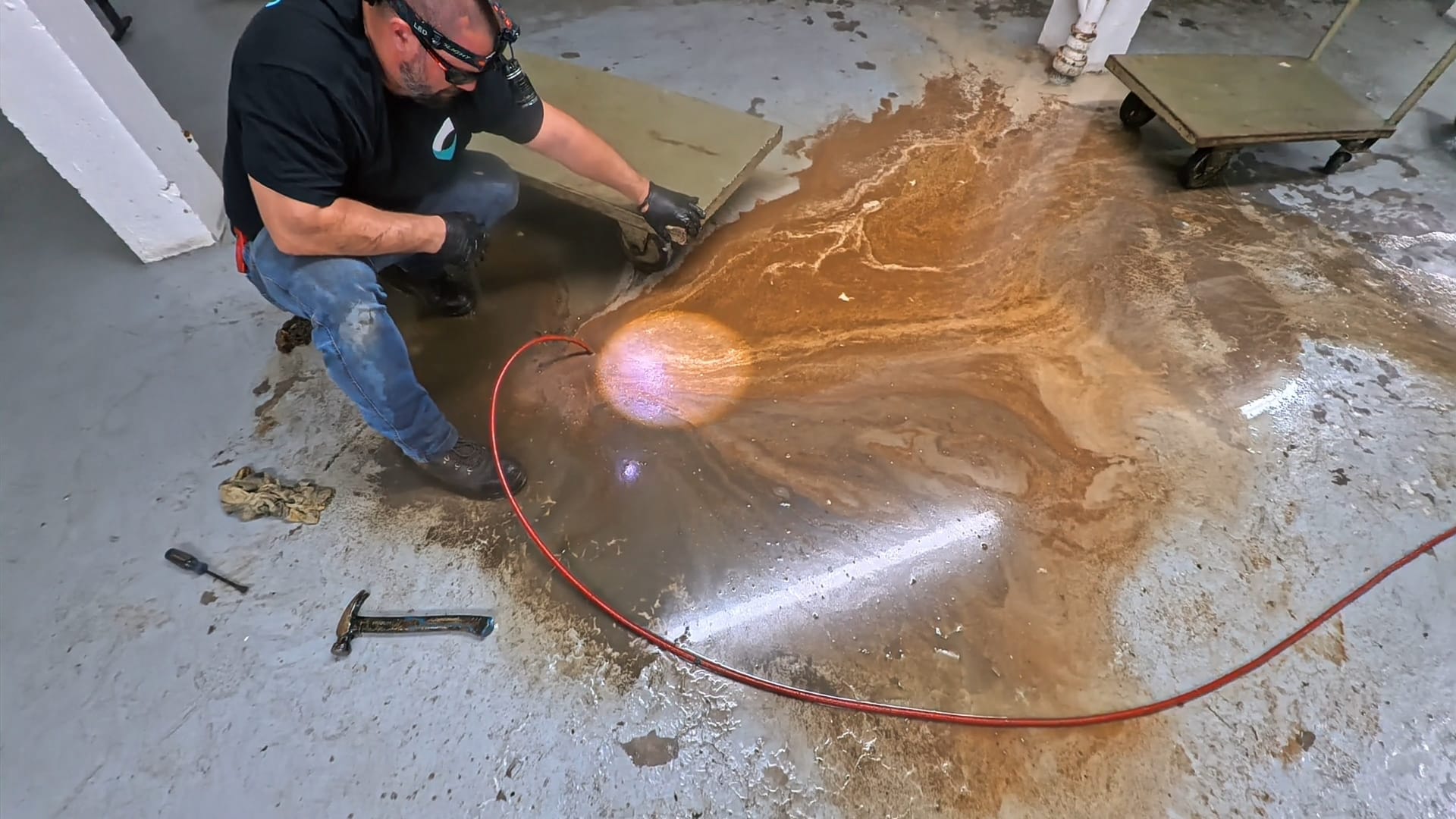 Technicien Flow Pro Drain intervenant sur un drain de plancher de restaurant qui refoule et provoque une accumulation d'eau sur le sol.