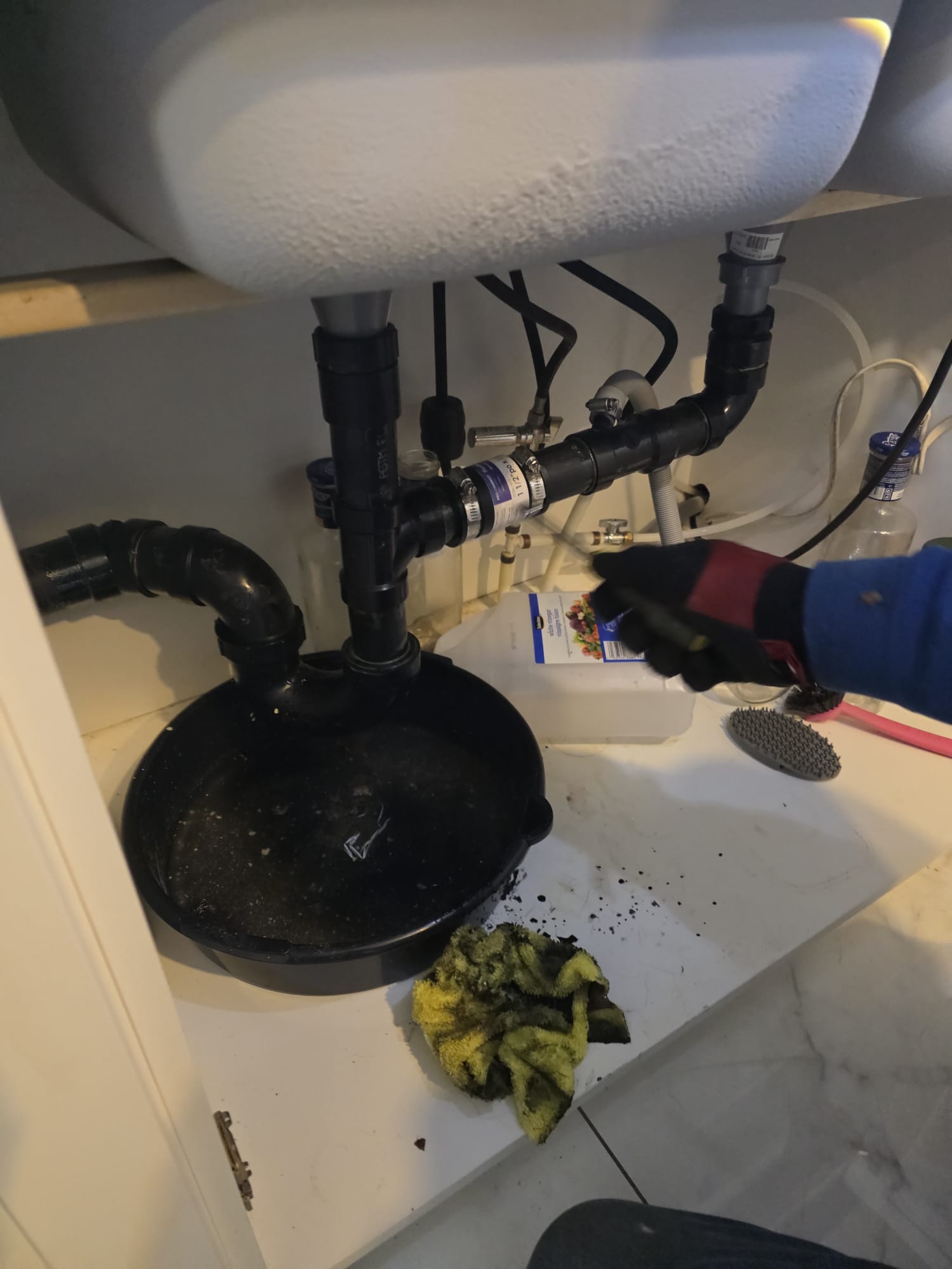 Technicien indiquant l’accès au drain de cuisine sous un évier